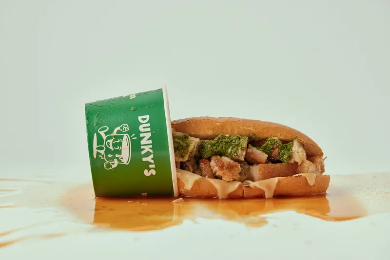 The Pork Belly roll with salsa verde beside a tipped-over Dunky's cup
